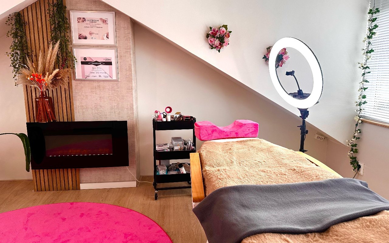 De behandelruimte met wimperstoel, ringlamp, sfeerhaard en een rond roze kleed