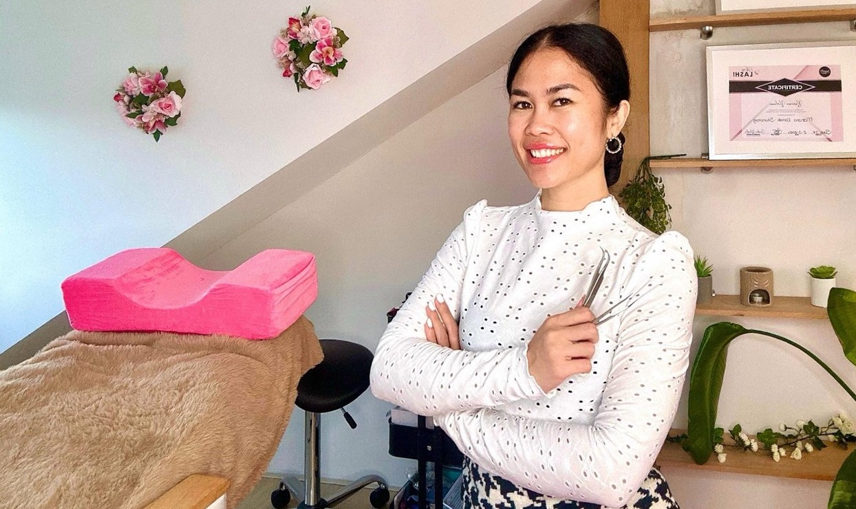 Medewerker van Super Beauty met een wimperpincet in de salon, naast de behandelstoel met roze kussen