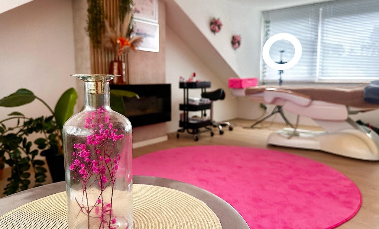 Glazen vaas met roze bloemen, op de achtergrond de behandelstoel op het roze kleed