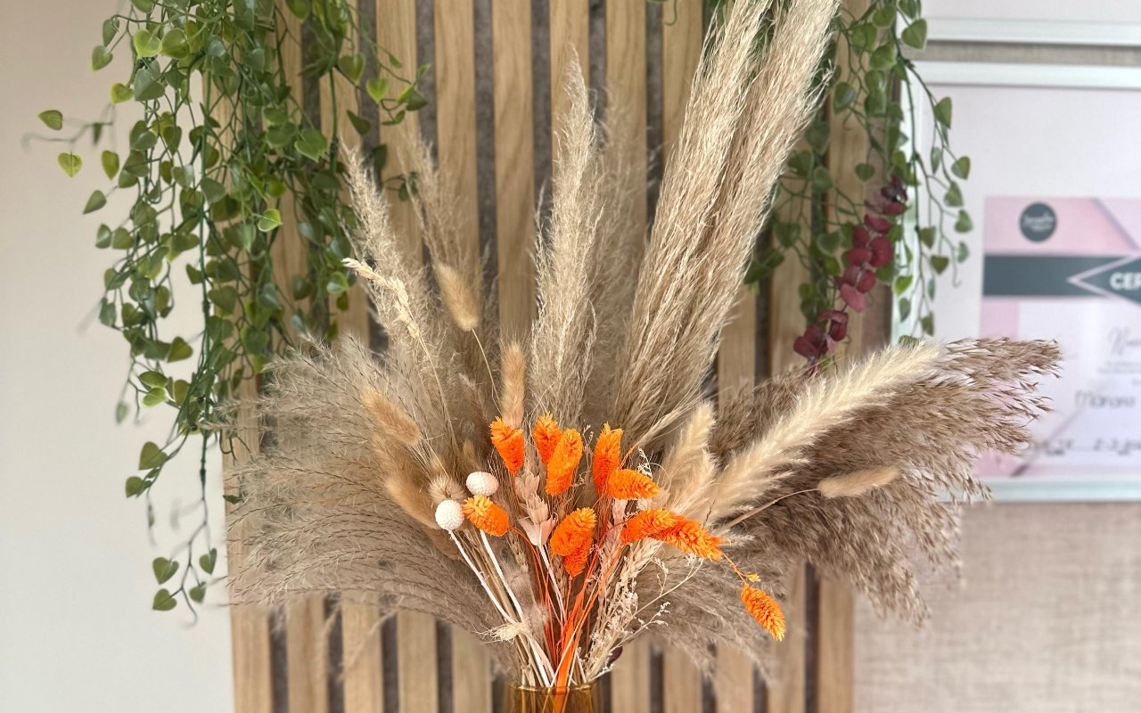 Boeket van droogbloemen en pampasgras voor een houten lattenwand in de salon