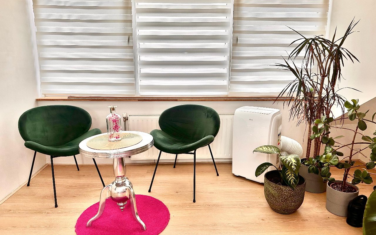 Zithoek met twee groene stoelen, planten en een rond roze kleed